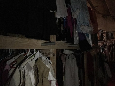 Costumes on racks in the dark.