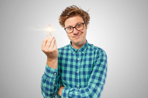 A nerd looking at camera with a light bulb in his hand and hes just had an amazing idea for something