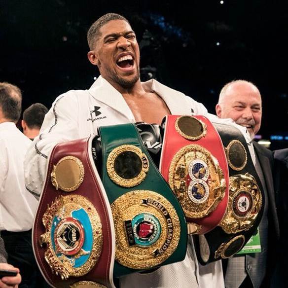 Joshua holding his 4 heavyweight belts